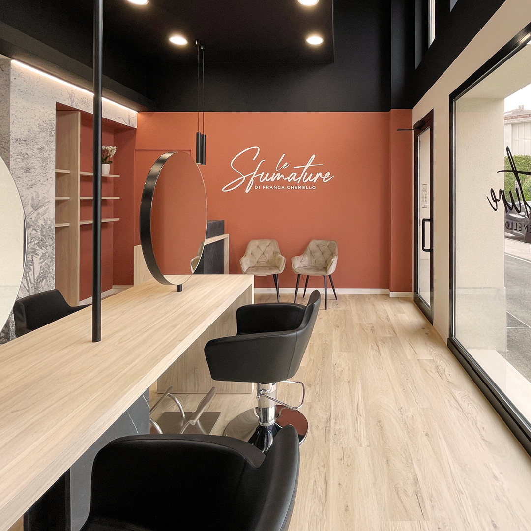 Immagine dell'area stilistica con pareti color mattone, poltrone nere e specchi. Mobili in legno 